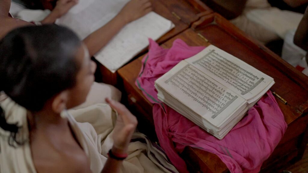 A young student is studying a religious text in a traditional classroom setting, focused and engaged.